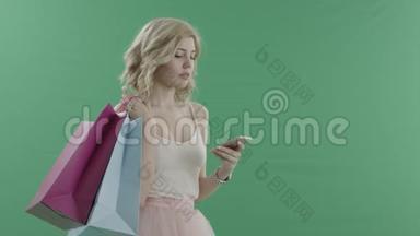 年轻有魅力的女人在等待一个拿着袋子对着<strong>绿色</strong>屏幕的人时，用手机<strong>上网</strong>